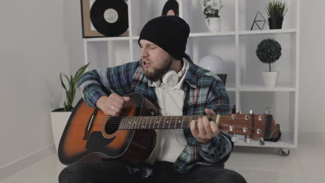 Male-Urban-Musician-Singing-And-Playing-Guitar-At-Home