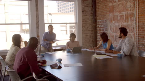 businessman standing to address boardroom meeting