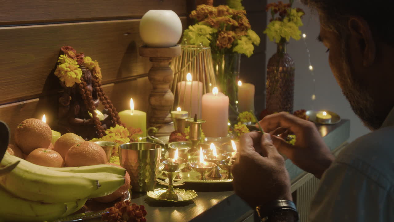Candles lit near fruit and statue