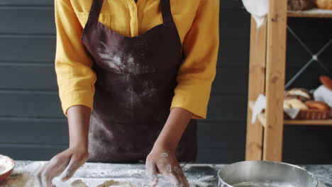 black female baker kneading dough on kitchen table