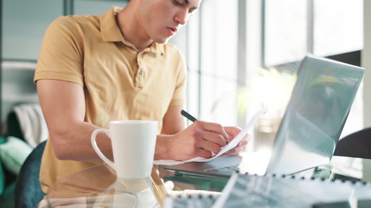 Man working on laptop with documents and coffee