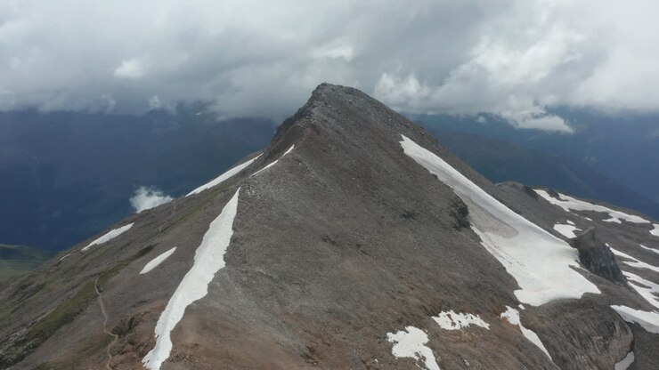 Ripresa aerea cinematografica della cima rocciosa di una montagna con neve che si scioglie