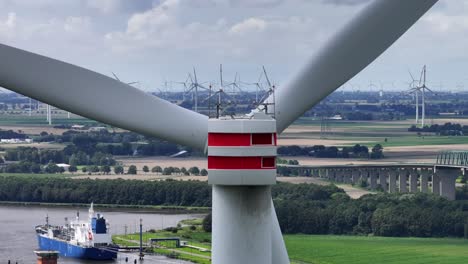 Wind-turbine-up-close,-in-the-background-several-other-wind-turbines-spinning,-producing-clean-energy,-parallax-effect