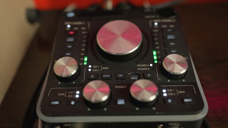 close-up of a sound mixer with illuminated knobs and controls, displaying a variety of settings and audio levels.the mixer is active, with lights indicating the adjustment of audio channels and levels