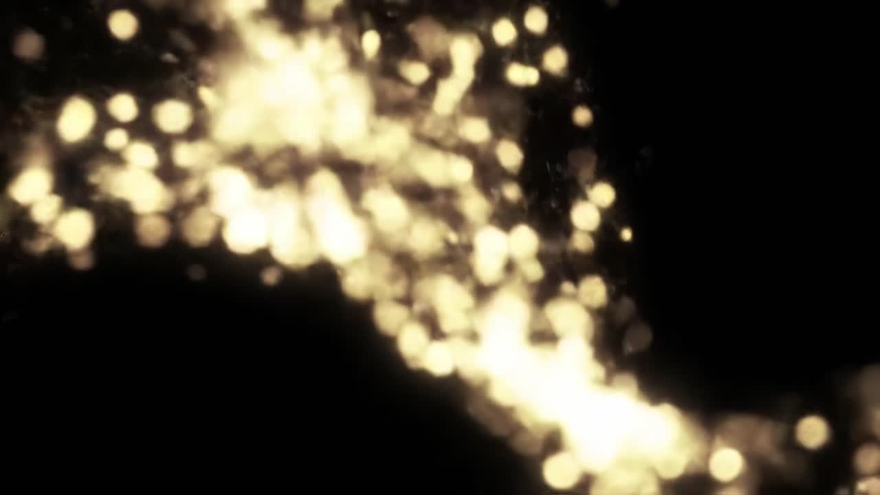 Golden particles dance gracefully in a dark environment, creating a captivating and enchanting display. The shimmering light evokes a sense of wonder and beauty in motion.