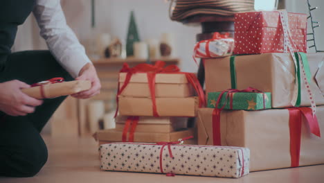 man arranging various christmas presents on floor at home