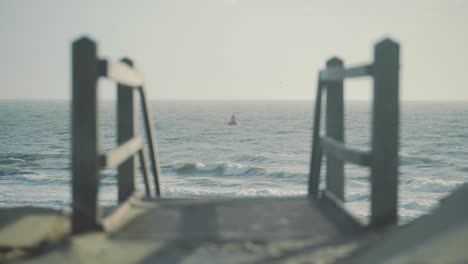 red buoy float floating in rough sea with staircase down to the beach