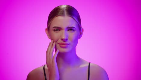 serious caucasian woman rubs over cheek due to toothache, studio shot