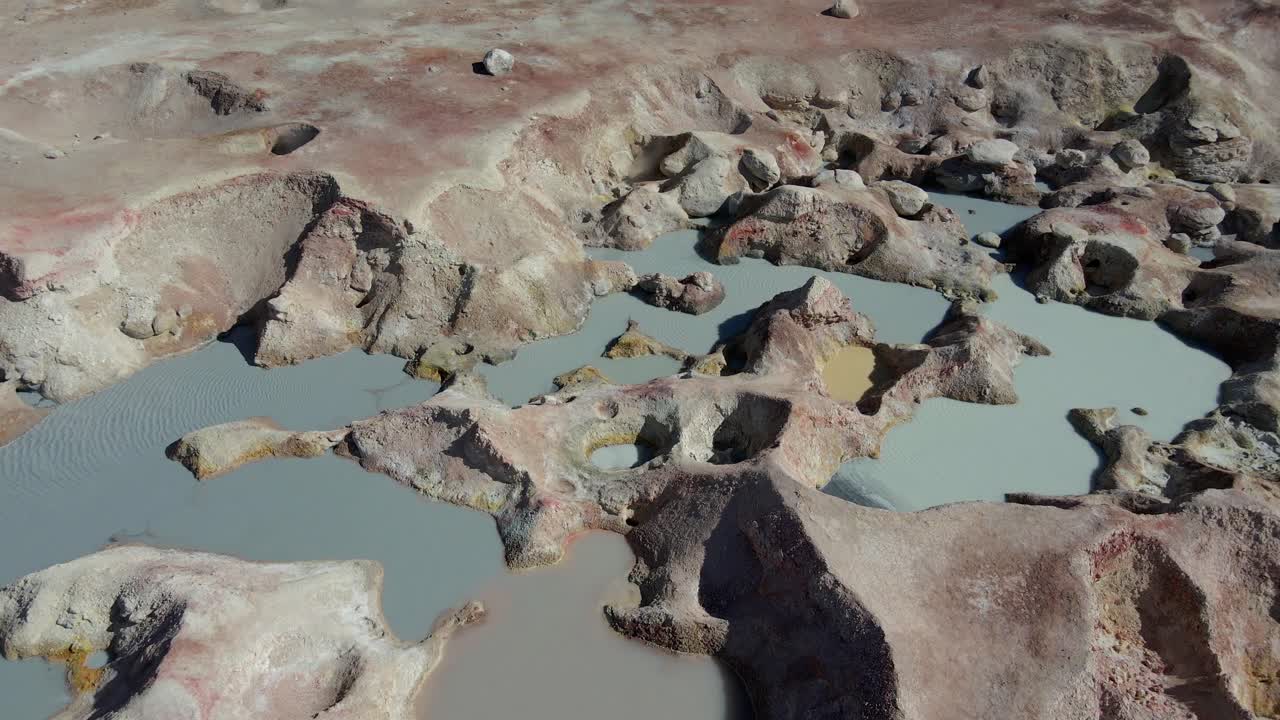 Top-down aerial of geyser field in Sol de Mañana with cracked earth and bubbling mineral pools