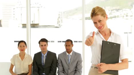 Businesswoman-giving-thumbs-to-camera-in-front-of-applicants