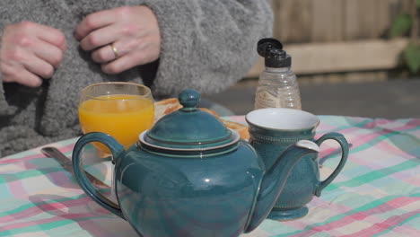 Person-in-robe-sits-down-to-enjoy-outdoor-English-breakfast,-close-up