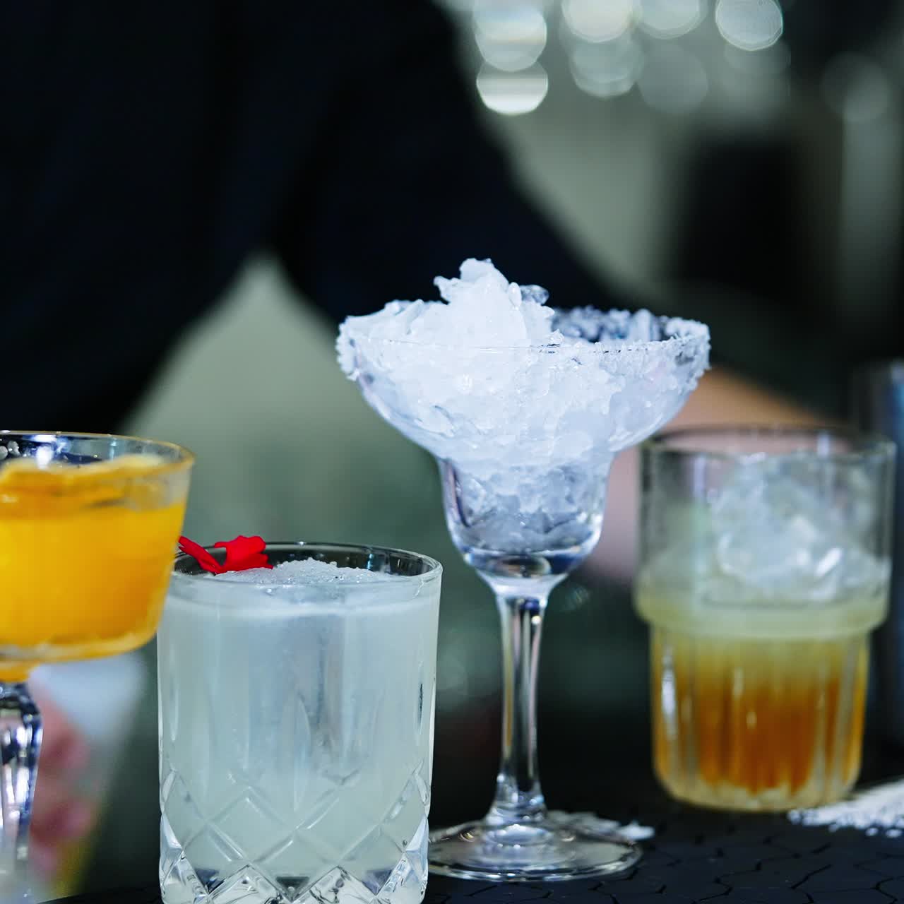 Preparation of cocktails in the bar. Bartender in black shirt fills the beaker with beverage and adds it to the glass