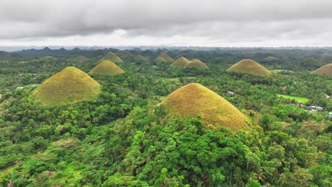 drone footage captures the unique cone-shaped chocolate hills of bohol, philippines, rising from dense greenery under a cloudy sky