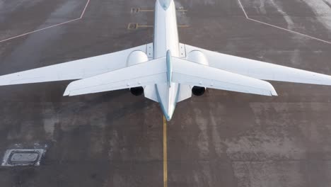 Rising-over-tail-of-white-private-jet-with-focus-on-back-wing,-aerial