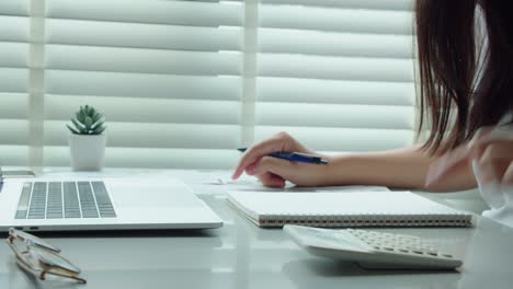 young woman calculating monthly home expenses, tax, credit card bills payment and bank account balance in living room at home.managing budget, entering data in computer application.