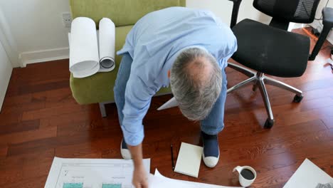 Man-using-digital-tablet-while-working-on-blueprints-4k