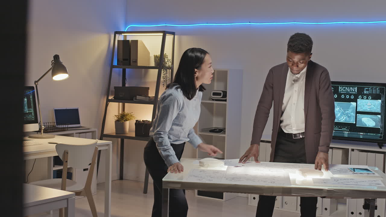 Male and Female Engineers Discussing Blueprints in Office