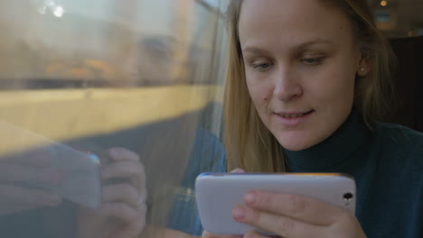 Woman-in-train-using-cell-and-looking-out-the-window