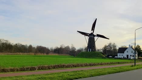 Eine-Sich-Bewegende-Holländische-Windmühle-Auf-Dem-Land-Mit-Sonnenuntergang
