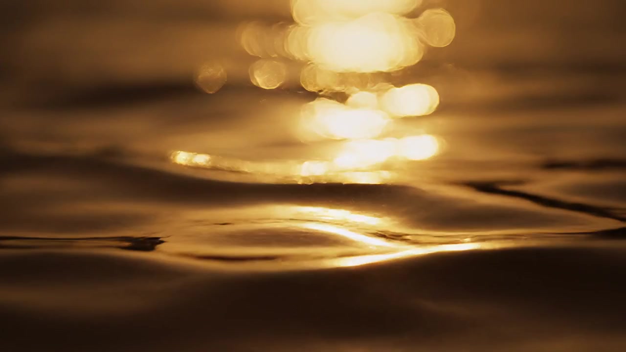 Riflessi dorati del tramonto e bokeh sulla superficie increspata dell'acqua