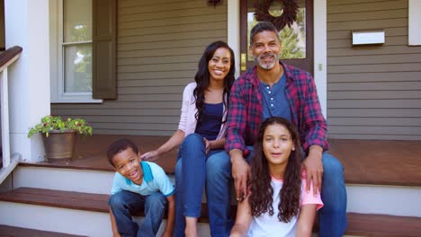 portrait of family sitting on steps of suburban home