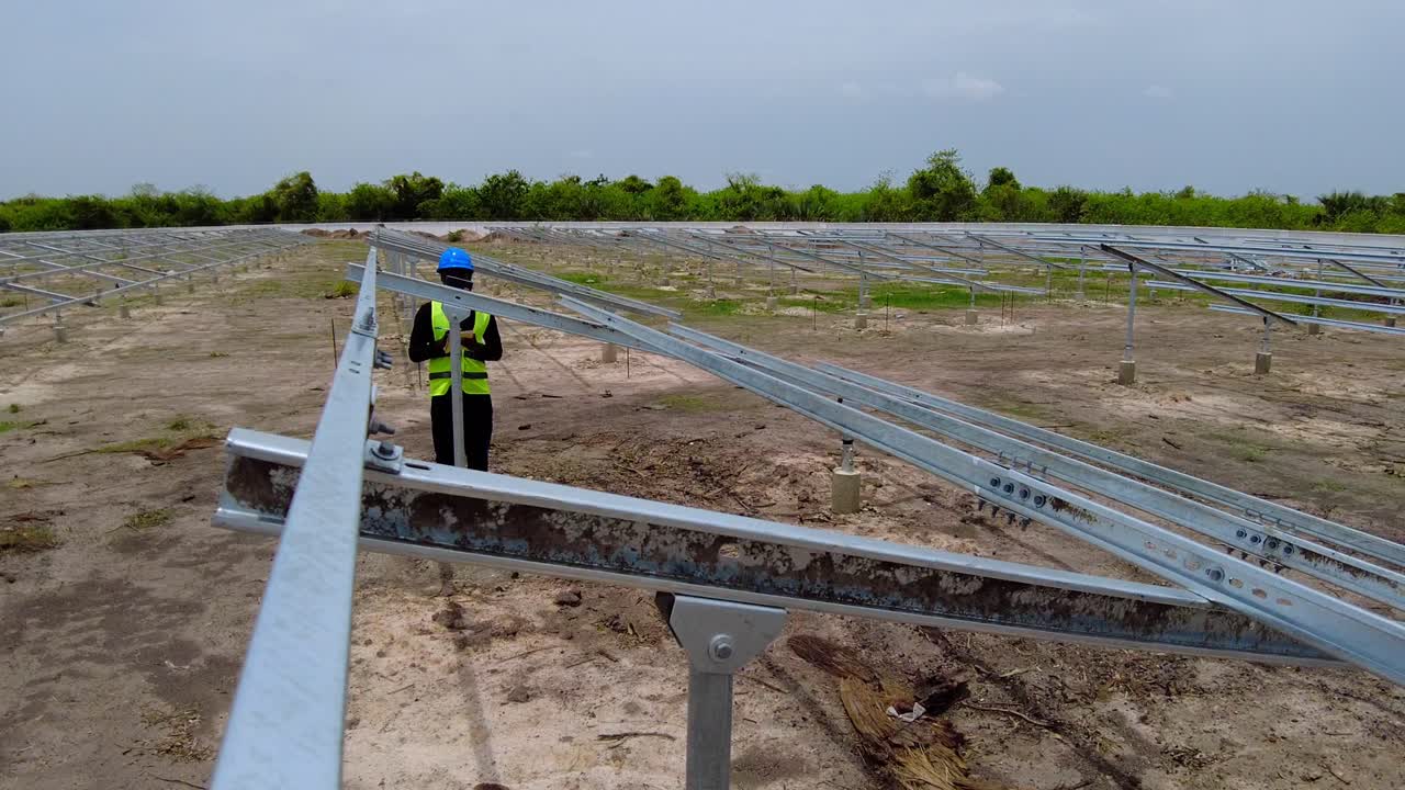 ingeniero africano con casco azul tomando mediciones del ángulo de inclinación de la estructura de la matriz de paneles solares - nawec gambia