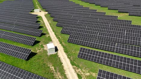 Paneles-Solares-Dispuestos-En-Un-Campo-Bajo-La-Luz-Del-Sol,-Vista-Aérea