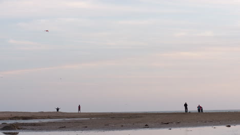 Family-Enjoying-Flying-A-Kite-At-Beach-River-Location,-SLOW-MOTION