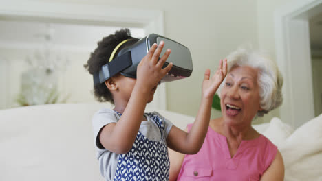 una abuela afroamericana feliz con su nieta usando auriculares vr en la sala de estar