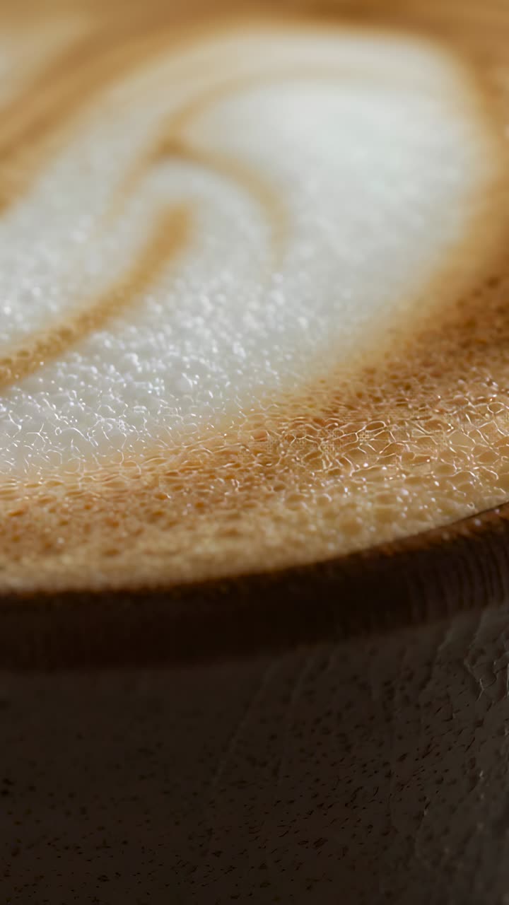Vertical video: Shifting focus and angle camera showing ceramic cup with latte art, crema on table