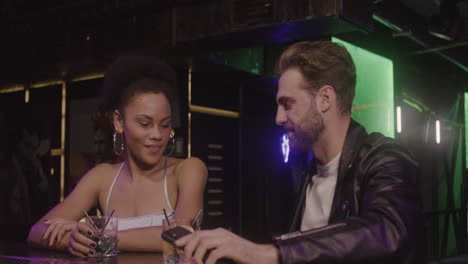 multiethnic couple taking a selfie photo while sitting at bar counter