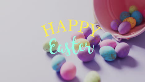 Animation-of-happy-easter-text-over-colourful-easter-eggs-and-pink-bucket-on-purple-background