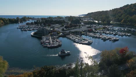 Drone-shot-of-a-park-that-looks-like-an-island-with-boats-near-a-forest-on-a-clear-sunny-day