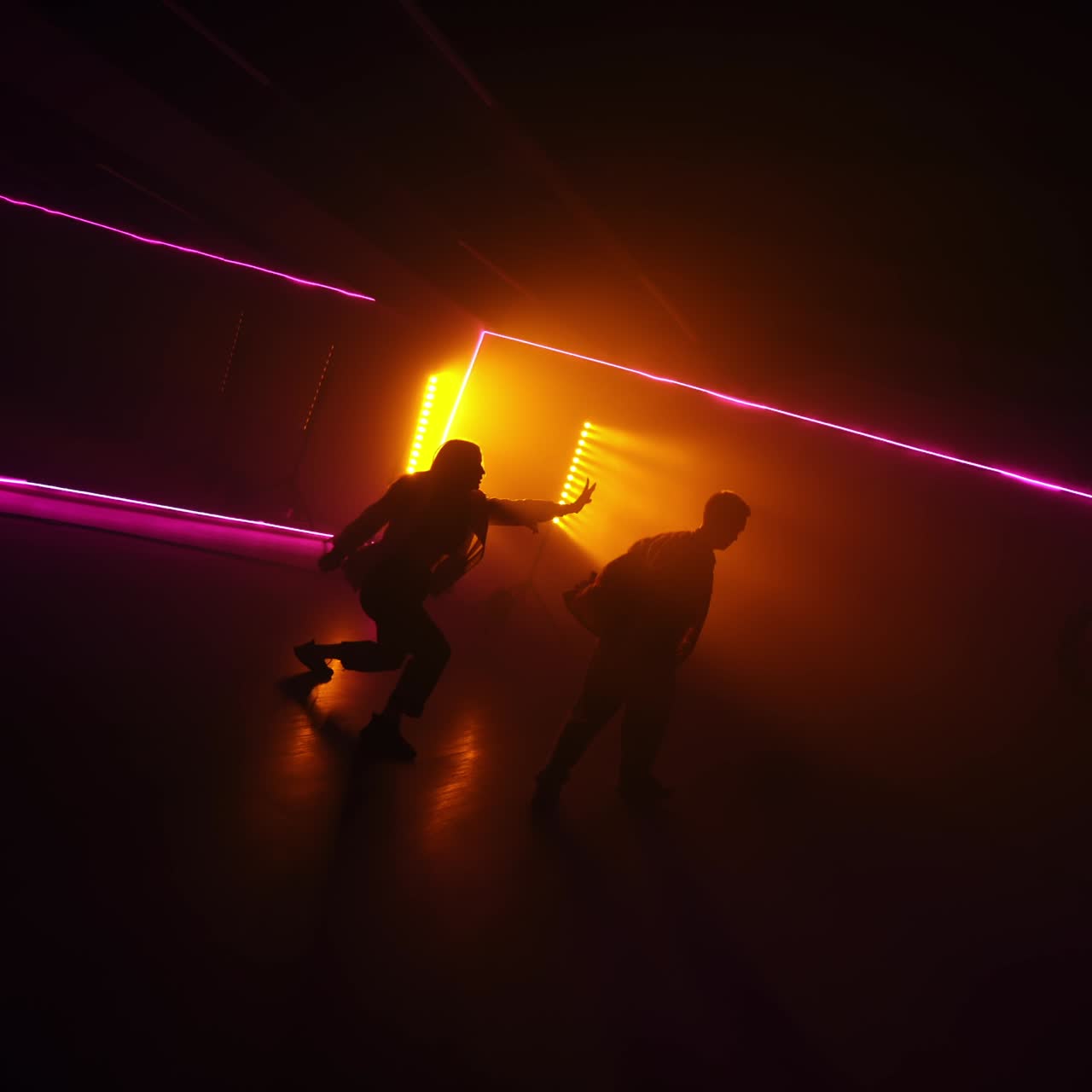 Young sportive people perform pair dance in dark studio. Contemporary dance style in front of projector