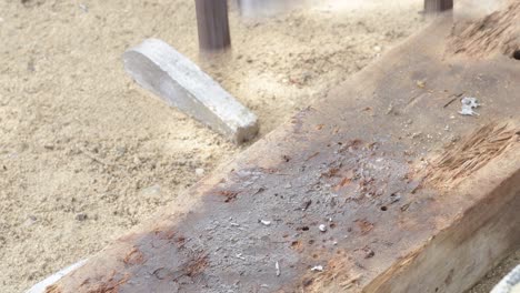 Molten metal pouring into mold on sandy surface, craftsmanship in action