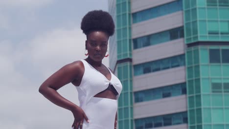 a young black girl in a white dress overlooks the city from a rooftop vantage point