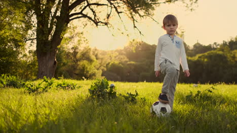 In-Zeitlupe-Spielt-Der-Junge-Lustig-Mit-Einem-Fußball-Auf-Einer-Wiese-Bei-Sonnenuntergang