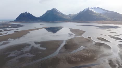 Paisaje-Islandés-Ríos-Glaciales-Negros-Panorámica-Aérea-Montañas-Nórdicas-Nevadas