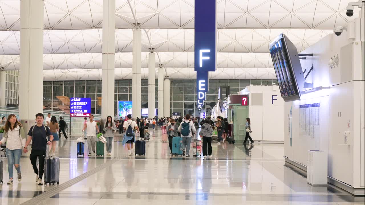 People walking through a busy modern airport terminal with luggage