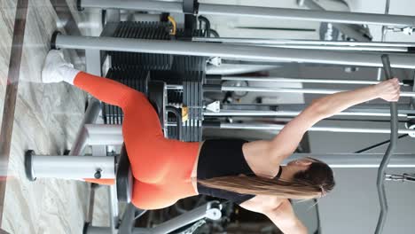 athletic woman doing intense strength training with dumbbells in a modern gym. vertical video