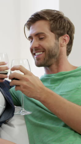 retrato de una pareja joven sentada en el sofá con un vaso de vino rojo