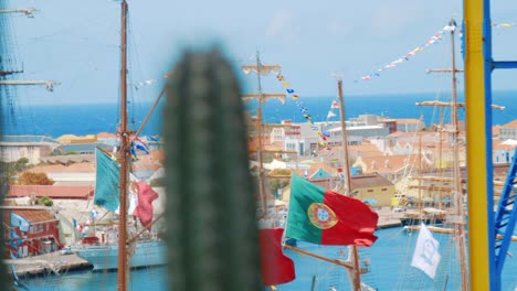 barco alto con muchas banderas ondeando en el viento con los colores nacionales de méxico, perú y portugal mientras está amarrado en curaçao