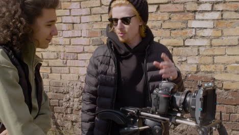 close up view of two production co workers talking and setting up a camera in the street