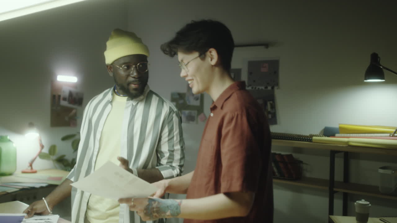 Two colleagues discussing design documents in a creative workspace