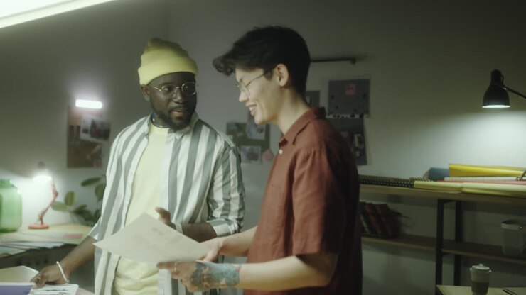 Two colleagues discussing design documents in a creative workspace