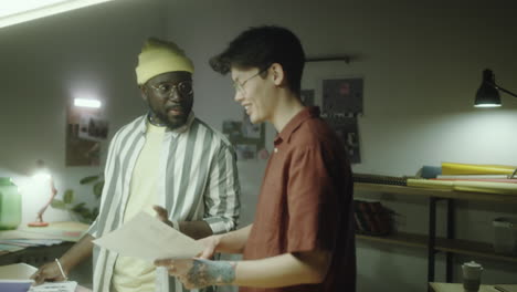 two colleagues discussing design documents in a creative workspace