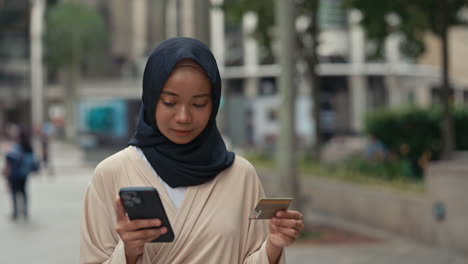 muslim woman making online payment with smartphone and credit card