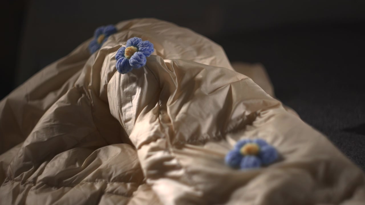 Grandangolo, cappotto trapuntato con fiore all'uncinetto, illuminazione a bassa chiave e profondità di campo ridotta, due decorazioni in filato blu