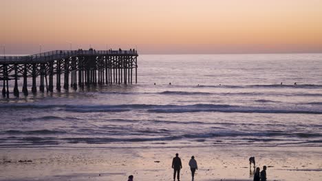 pacific beach california pier sunset with waves crashing on beach - slow motion of pier in blue hour