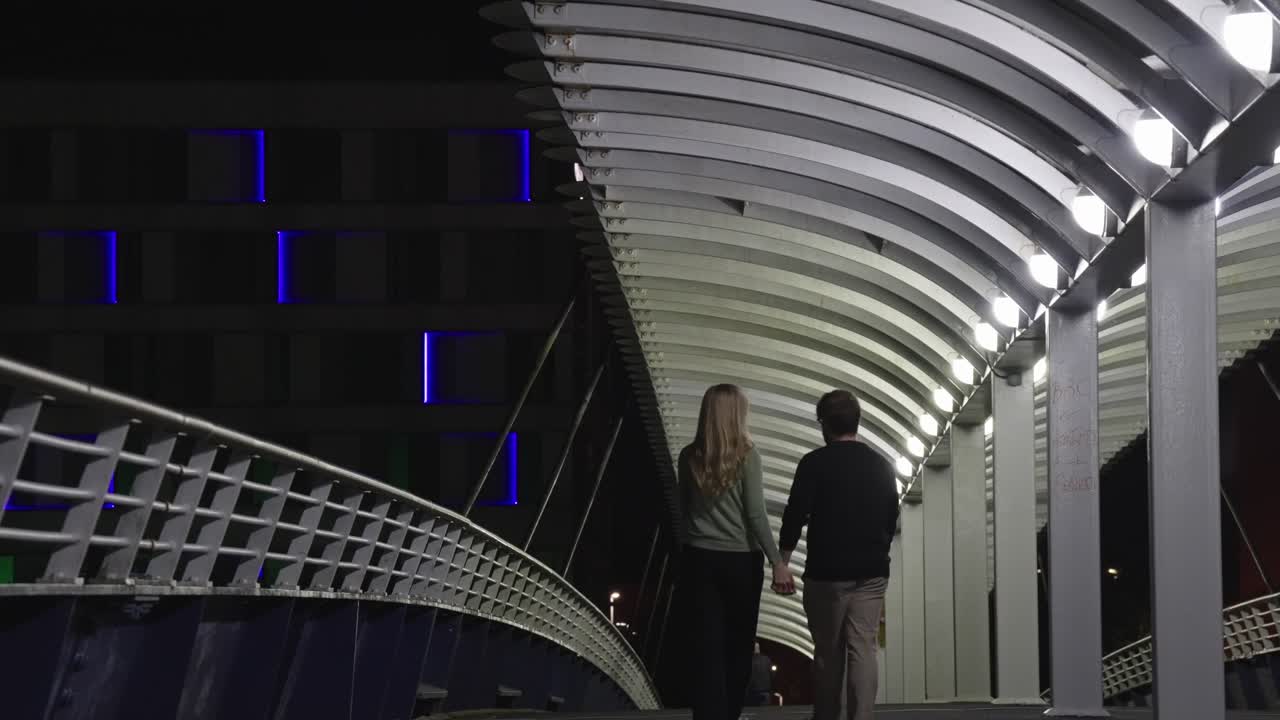 Loving young couple, walking, kissing, bridge location, night scenery